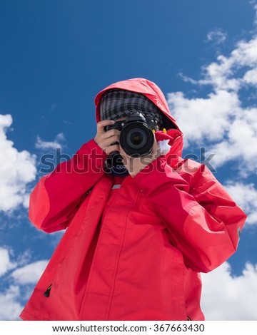 Asian tourist  girl on vacation photographing with a dslr camera with blue sky background