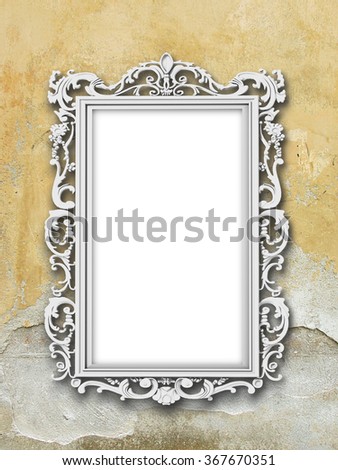 Close-up of one silver Baroque picture frame on grey and ochre cracked plaster wall background