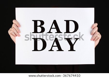 Woman holding poster with text Bad Day in front of her face isolated on black