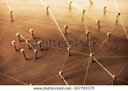 Linking entities. Network, networking, social media, internet communication abstract. A small network connected to a larger network. Web of gold wires on rustic wood. Royalty-Free Stock Photo #367703579