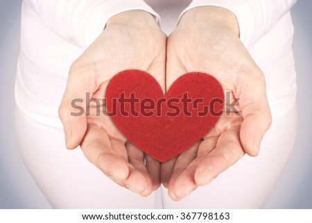 Photograph of a woman's hands holding a heart fabric. Greeting card for Valentine's Day. Stock photography.