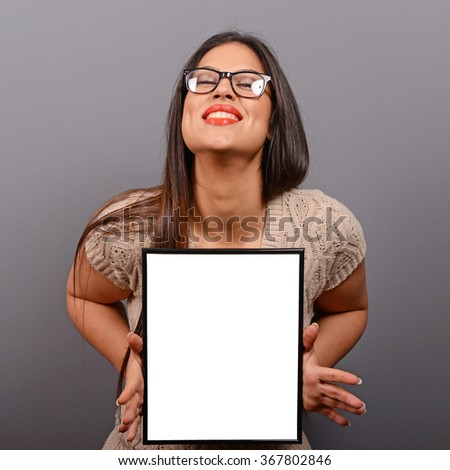 Portrait of smiling woman holding blank photo frame against gray background