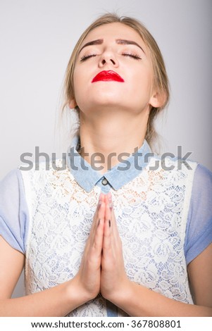 cute blonde girl praying with folded hands isolated