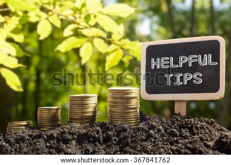 Helpful tips - Financial opportunity concept. Golden coins in soil Chalkboard on blurred urban background