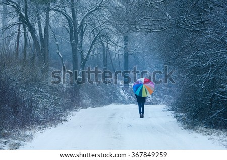 Alone girl in winter nature hold in hand beautiful umbrella with rainbow colors