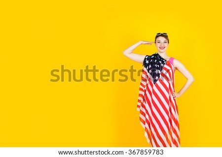Happy and smiling young girl with American Flag posing on yellow background.