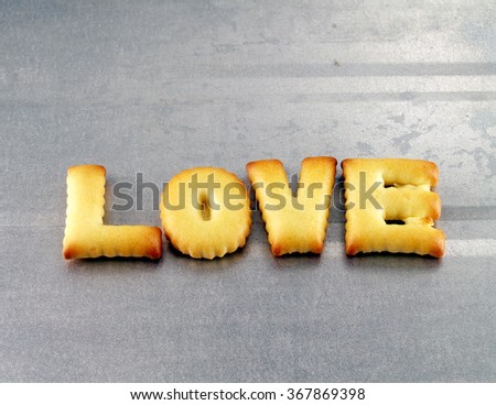 love word, biscuit cookies lettering on aluminum oven tray, preparing baking homemade cracker for valentine day, flat lay close up top view