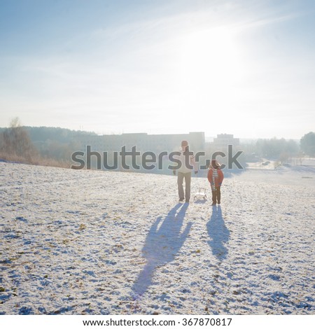 Dad and son having fun in the winter. Dad and son walking in winter on the background of the sun. concept of the relationship between father and son