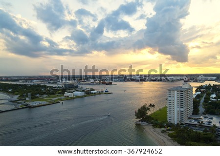 Beautiful marine view on harbour in small bay with houses boats and green grass on cloudy sunset background, horizontal picture