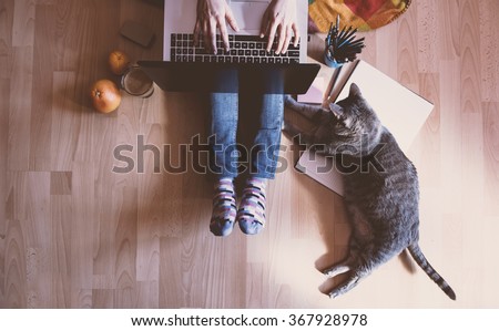 Creative workspace: girl working at the computer assisted by her cat. Royalty-Free Stock Photo #367928978