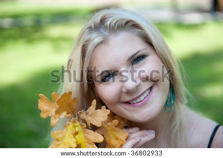 close-up Picture of a happy pretty blond girl and the autumn yellow leaves in the park