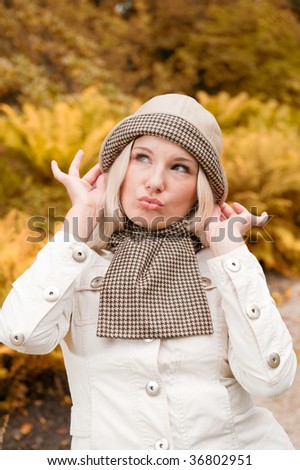Picture of a young beautifull british girl walking in an autumn park and sending a kiss
