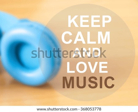 Blue headphones with "keep calm and love music" quote on wooden background