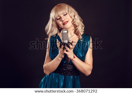 Singing Woman with Retro Microphone. Beauty Glamour Singer Girl Portrait. On black Background. Vintage Style. Karaoke Song