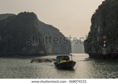 Beautiful limestone cliff and fishing boat in Ha Long bay, Vietnam. Cloudy winter weather