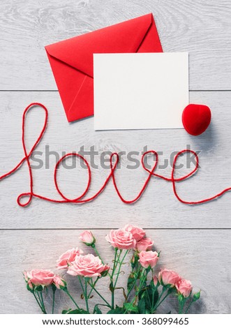 Red envelope with letter and flowers on a wooden background. Valentines Day background