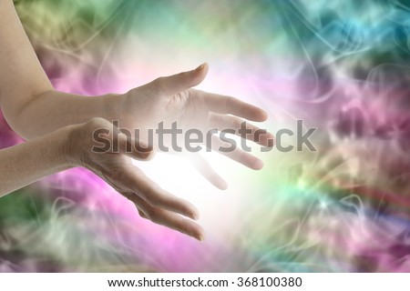 Beaming healing energy - Outstretched female healing hands with white light between and a vibrant multicolored flowing energy field background Royalty-Free Stock Photo #368100380