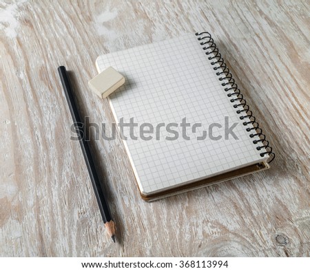 Photo of blank sketchbook with a pencil and eraser on light wooden background with soft shadows. Mock-up for branding identity.