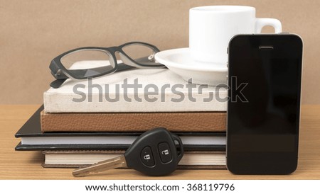 coffee,phone,car key,eyeglasses and stack of book on wood table background