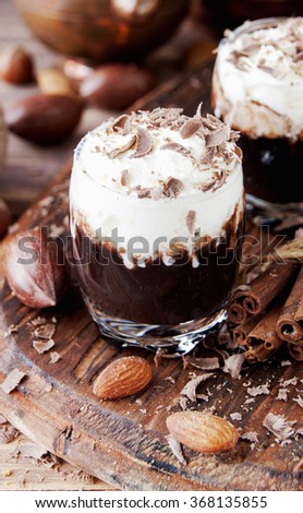 hot chocolate in glass cups and cream with nuts and cinnamon on a wooden table selective focus