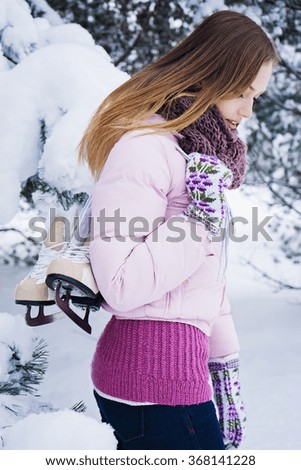 nice brunette woman with pair of white skates in snowy forest