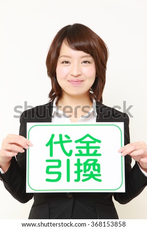 young Japanese businesswoman holding a message board with the phrase CASH ON DELIVERY in KANJI