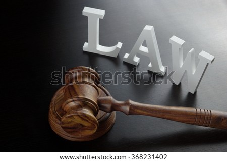 Judges Gavel And White Sign Law Made From Wooden Letter On The Black Wood Table  Background In Back Light, Close Up, Conceptual Image.