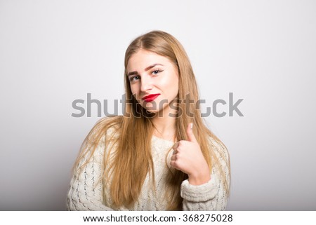 Pretty blond girl showing thumbs up gesture, cool, isolated