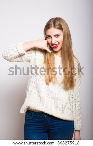 Closeup portrait of beautiful young woman making call me gesture on grey background