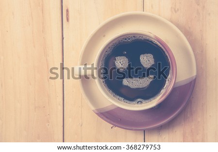 Espresso Cup with smiley face on wooden table, overhead view
,vintage color toned image