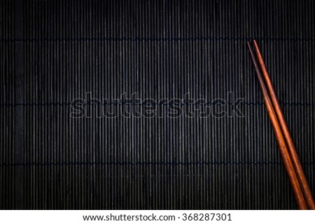 wooden chopsticks on the black bamboo mat background