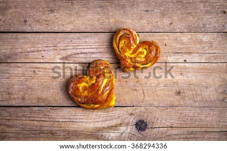 Homemade pastries. Bun heart on wooden background. Food