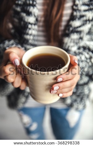 Girl's hands holding a cup of coffee. Stylish manicure and nails