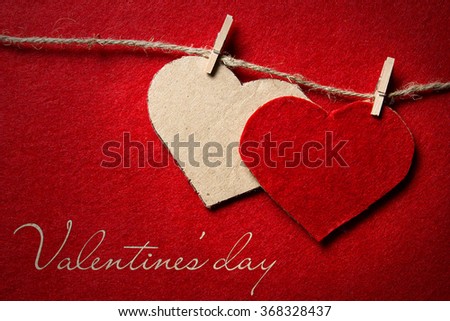 Valentines day. Two hearts from felt and cardboard on rope with clothespin on red background with the gradient effect