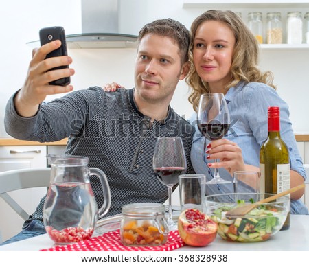 Young couple having dinner at home. Taking selfie with mobile phone.