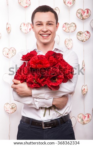 Beautiful young man  in love with a bouquet of flowers. Valentine's Day. Picture taken in the studio.