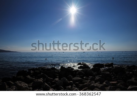 Photo closeup of beautiful blue sea shore marine peaceful water stony coast sun high in sky over seascape background, horizontal picture 