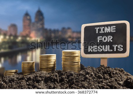 Time for results - Financial opportunity concept. Golden coins in soil Chalkboard on blurred natural background.