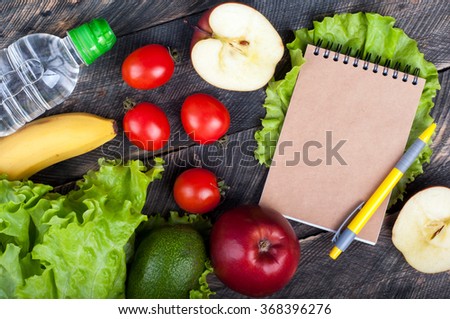 Fresh organic vegetables and fruits. Lettuce, avocado, apple, banana, water bottle, open blank notebook and pen on wooden background. Healthy food and healthy life concept. Top view Royalty-Free Stock Photo #368396276