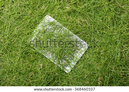 Tablet lying on the green grass texture background