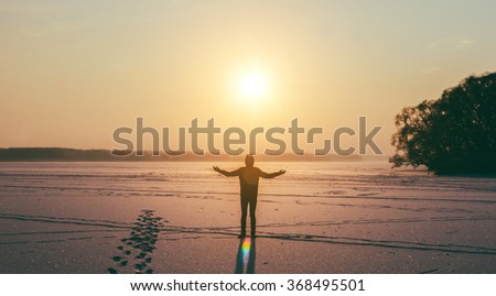 Man and sun on the frozen winter lake