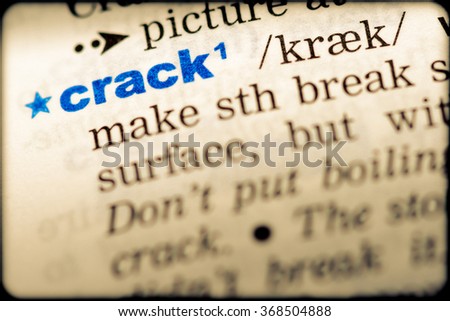 Close-up of word in English dictionary. Crack, definition and transcription