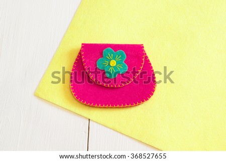Felt pink wallet handmade on the yellow felt and white wooden background  Royalty-Free Stock Photo #368527655