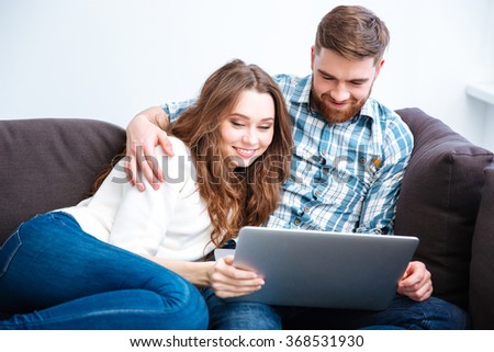 Portrait of a happy couple using laptop computer on the sofa at home