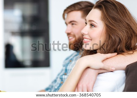 Portrait of a happy couple watching TV on the sofa at home