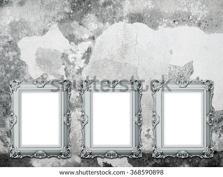 Close-up of three silver Baroque picture frames on scratched weathered concrete wall background