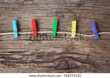 Colored clothespins on rope on a wooden table or board for background. Space for text.