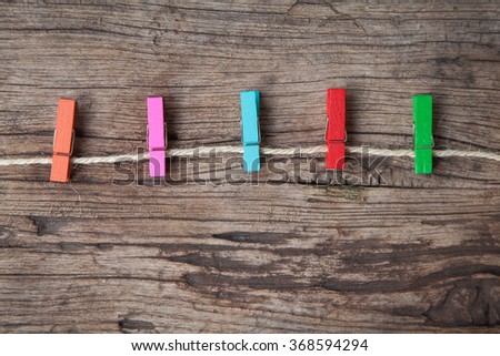 Colored clothespins on rope on a wooden table or board for background. Space for text.
