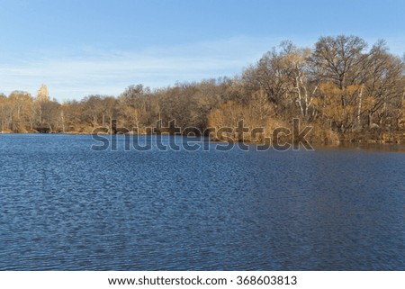 Central Park picture with a lake and trees. All reflecting on lake. Tree without foliage.