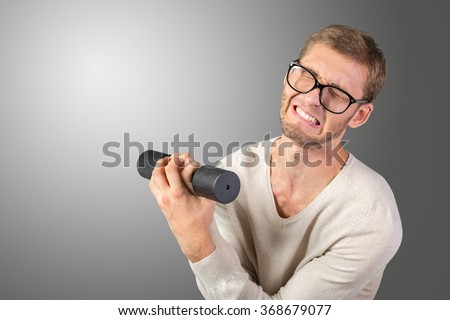 Funny weak man tries to lift a weight Royalty-Free Stock Photo #368679077